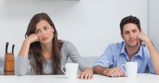 Tired couple sitting at the table with a cup of coffee